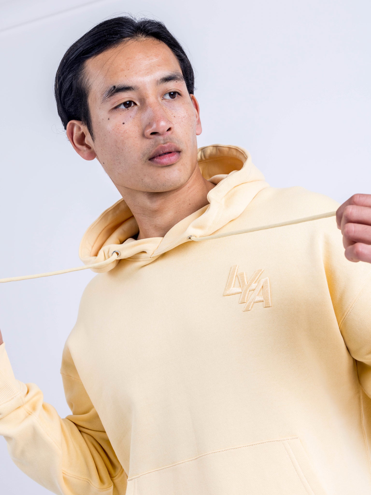 Model wearing the Sunny Yellow Organic Cotton Hoodie by LoveYouAll in an urban setting, highlighting its vibrant color and relaxed fit.