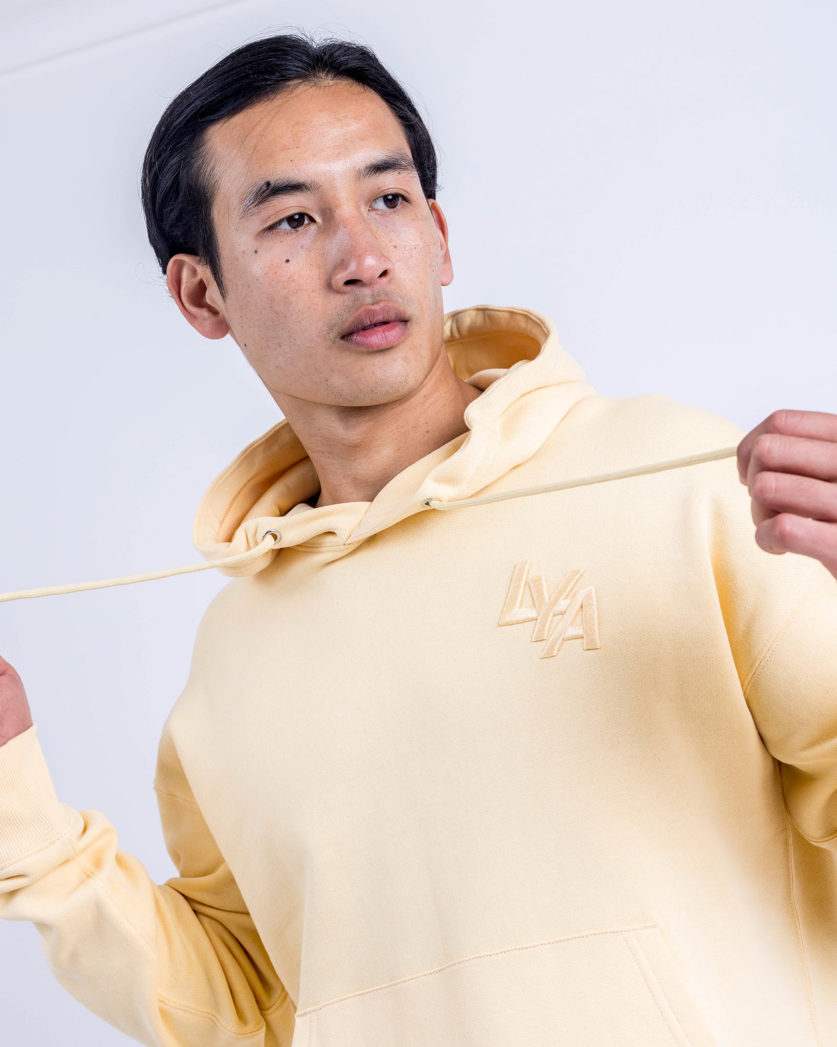 Model wearing the Sunny Yellow Organic Cotton Hoodie by LoveYouAll in an urban setting, highlighting its vibrant color and relaxed fit.